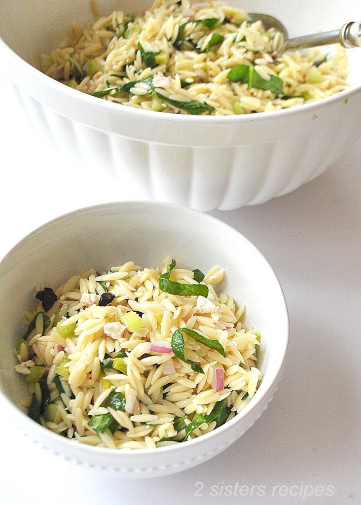 A white bowl filled with orzo salad. by 2sistersrecipes.com