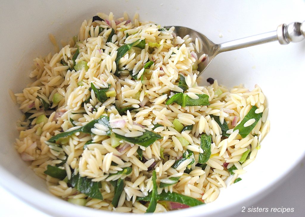 A white bowl filled with orzo pasta salad. by 2sistersrecipes.com