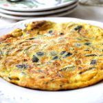 A large size zucchini omelet served on a round serving dish.