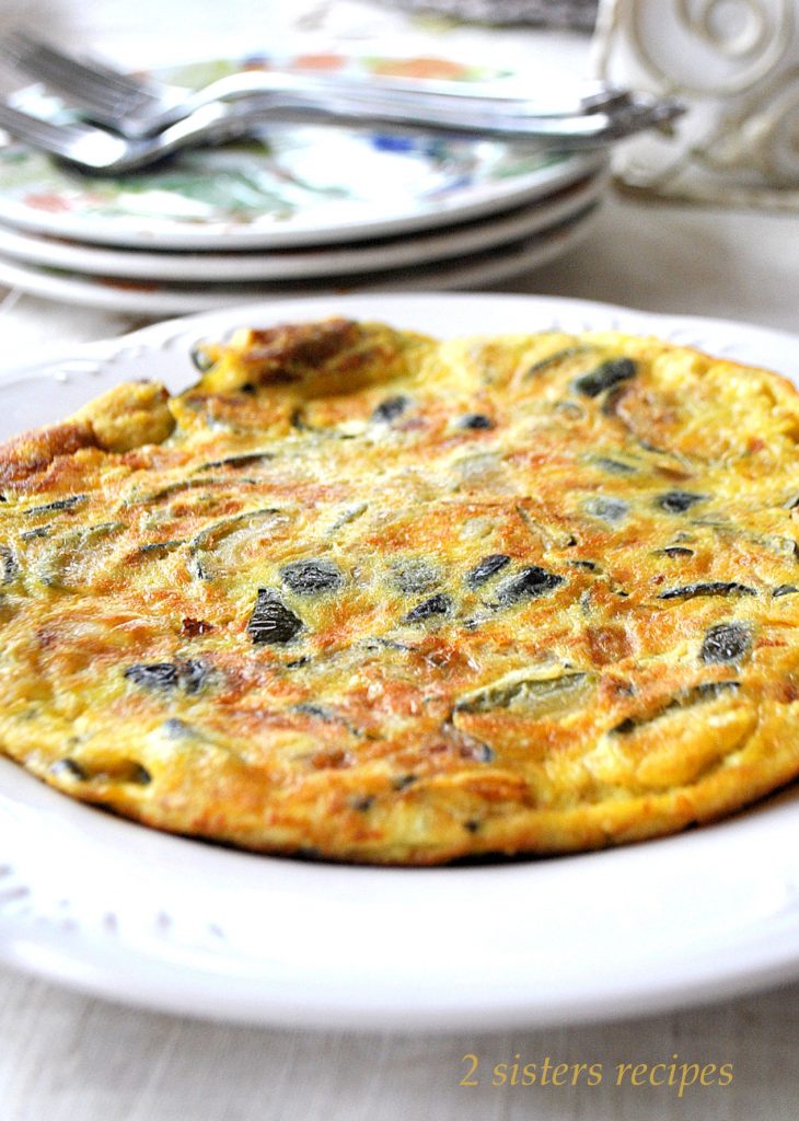 A large size zucchini omelet served on a round serving dish.