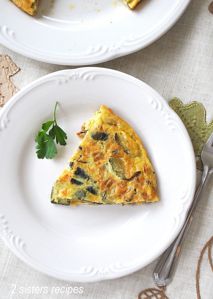 A slice of zucchini omelet served on a white dinner plate.