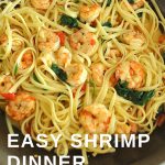 A large skillet filled with linguine pasta, shrimp, red peppers, and spinach.