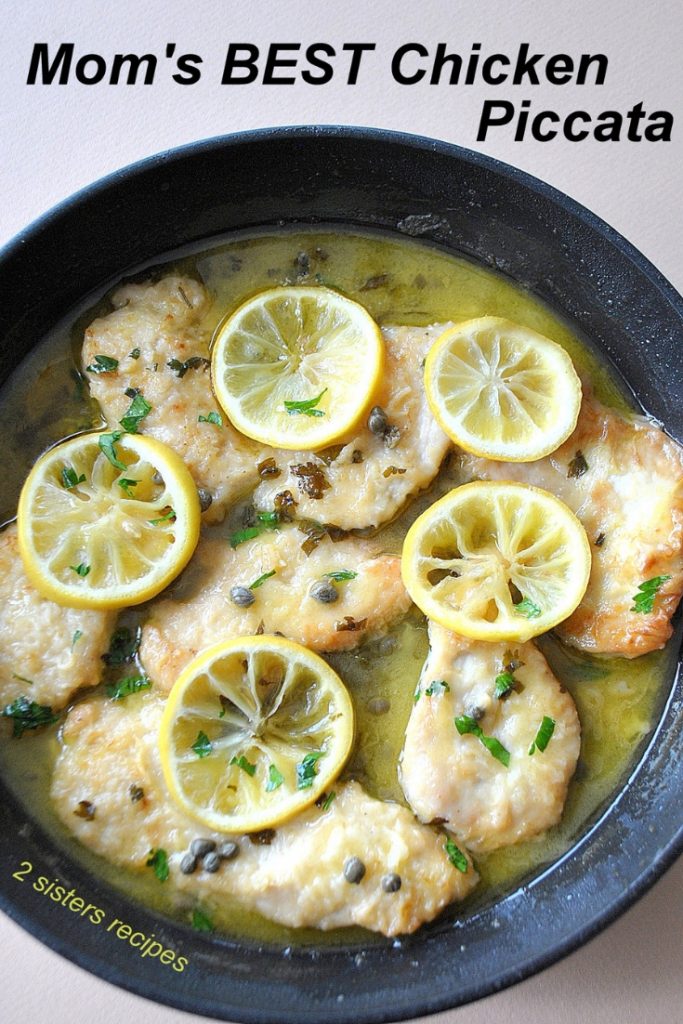 A black skillet filled with cooked chicken pieces with capers and lemon slices.