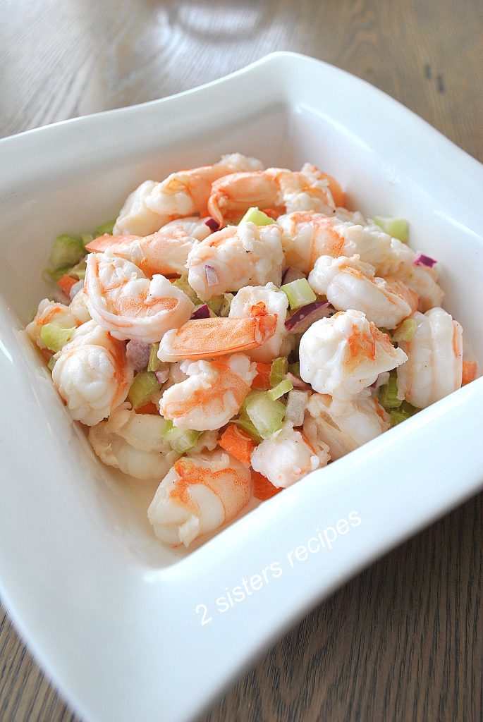 A square white bowl filled with shrimp salad.