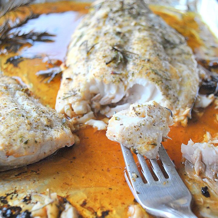 A forkful of cooked fish on a baking sheet. by 2sistersrecipes.com