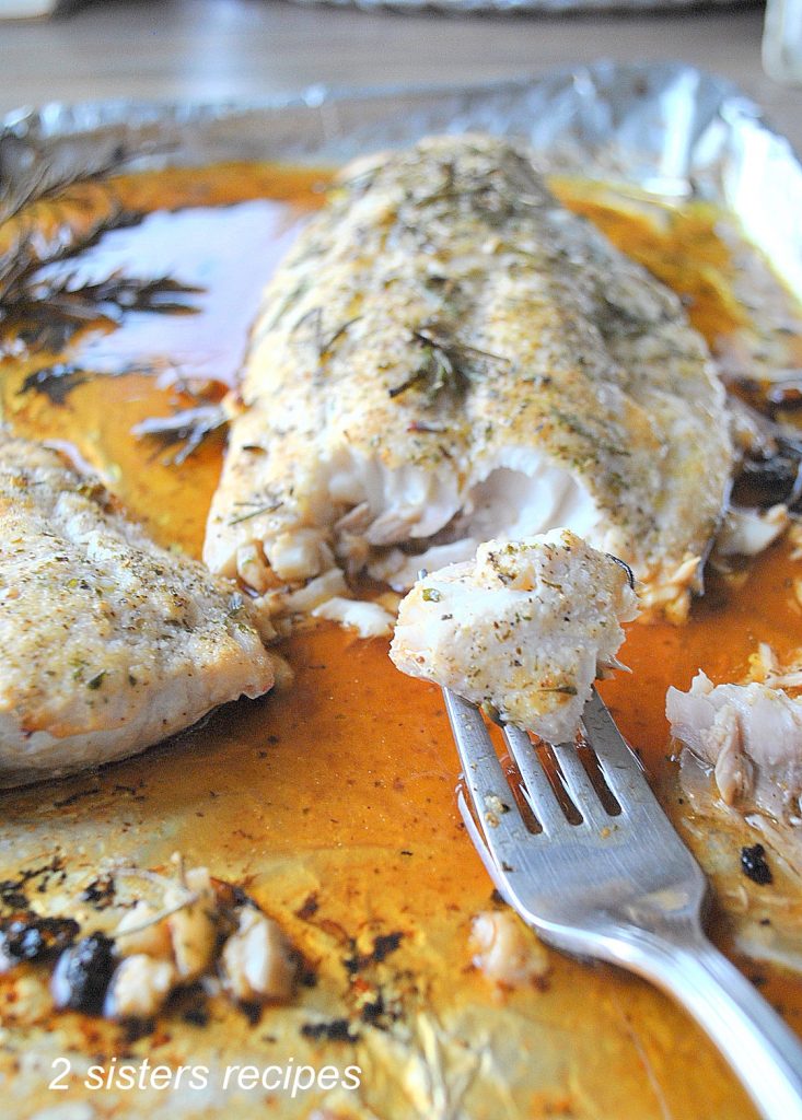 A forkful of cooked fish on a baking sheet.  by 2sistersrecipes.com