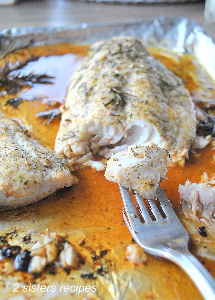 A forkful of cooked fish on a baking sheet. by 2sistersrecipes.com