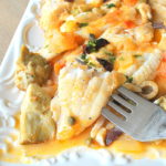 A forkful of Dover Sole Livornese fish served on a white platter.