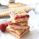 3 raspberry filled bars piled on one another and served on parchment paper.