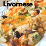A white platter with poached white fish, Dover Sole, topped with olives, capers and artichoke hearts.