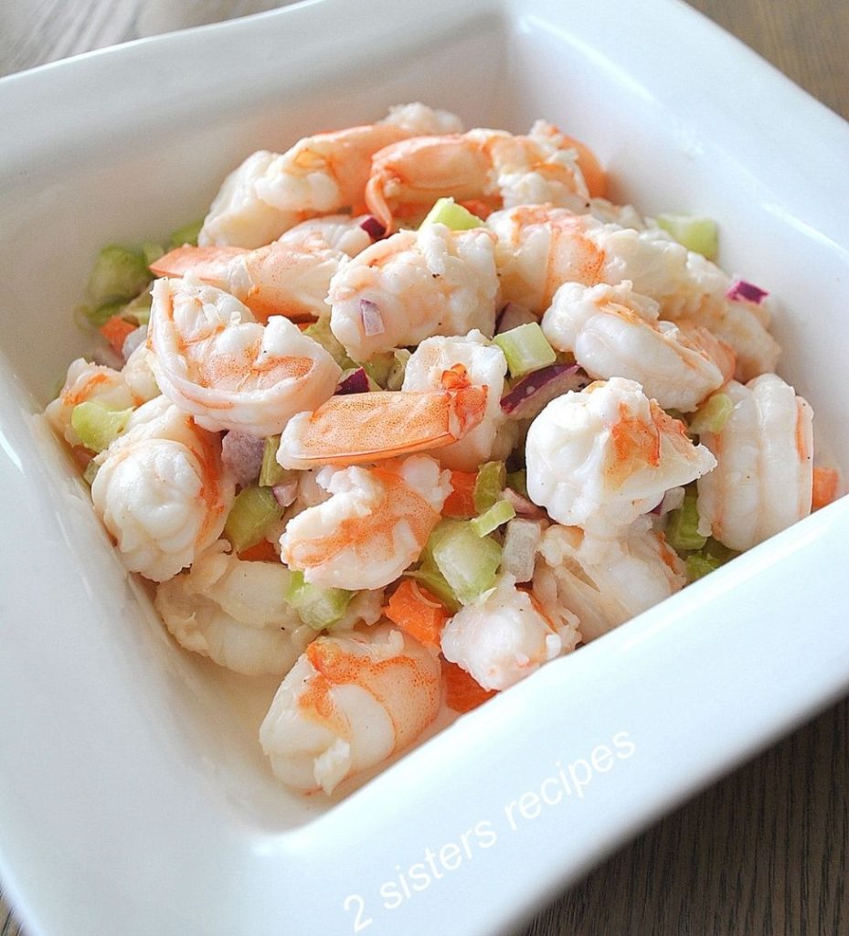 A white square bowl filled with shrimp salad.