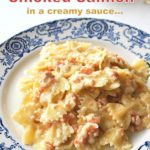 A blue and white plate filled with farfalle pasta tossed with pieces of smoked salmon cream sauce.