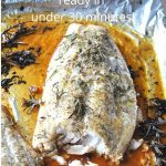 A large piece of white fish roasted on a foil wrap with roseamary sprigs.