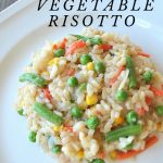 A white dinner plate with a serving of vegetable risotto.