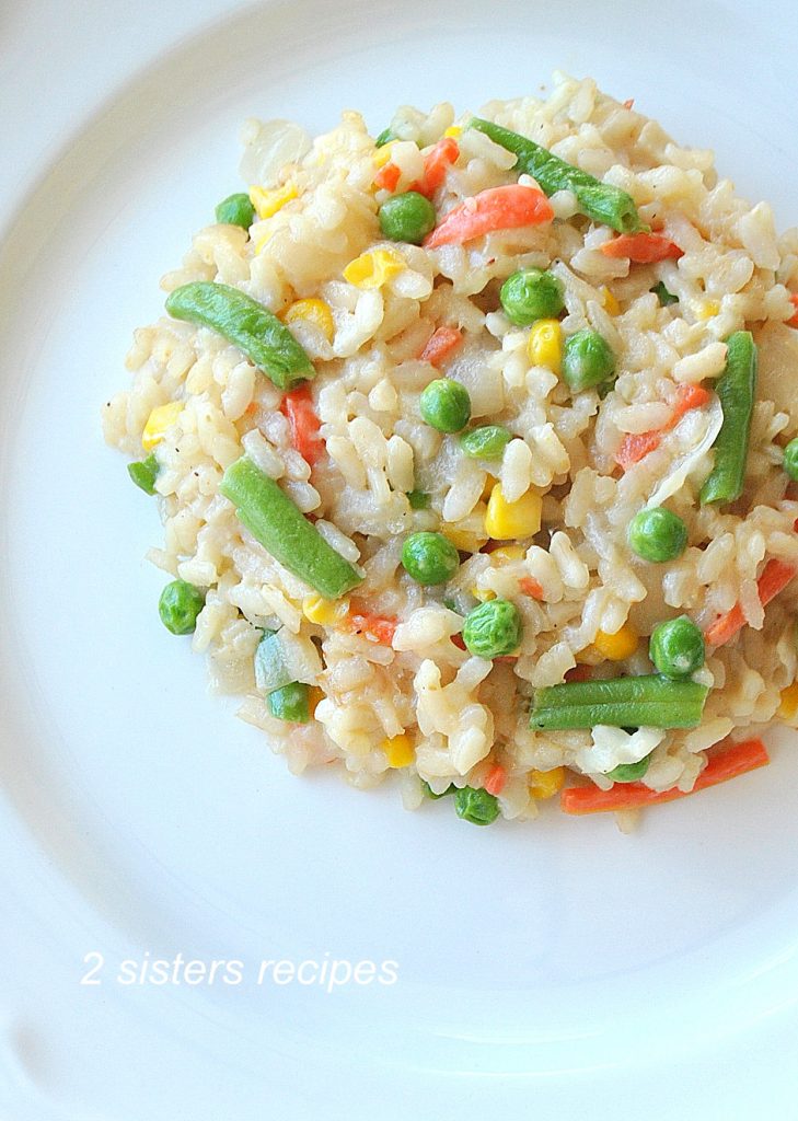 A risotto served on a white dinner plate with mixed vegetables. 