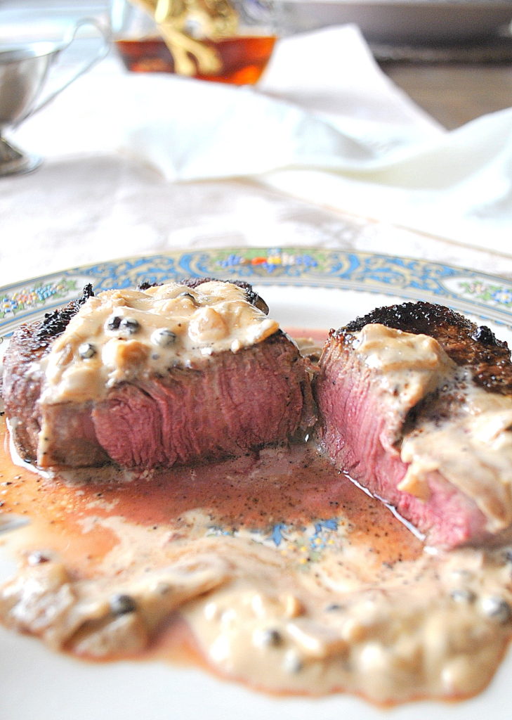 A steak sliced in half with a cream sauce on a dinner plate.   by 2sistersrecipes.com