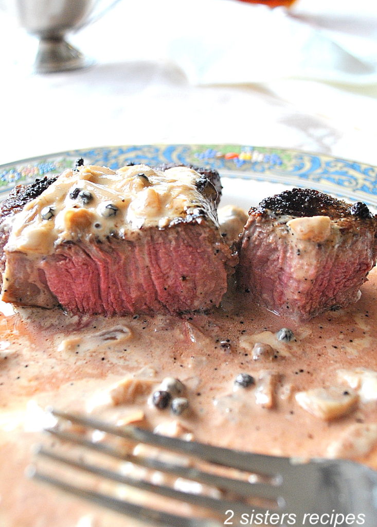 Steak is sliced down the center on a dinner plate. by 2sistersrecipes.com