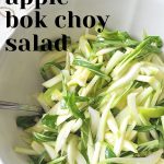 A large white bowl filled with thinly sliced bok choy and green apples.