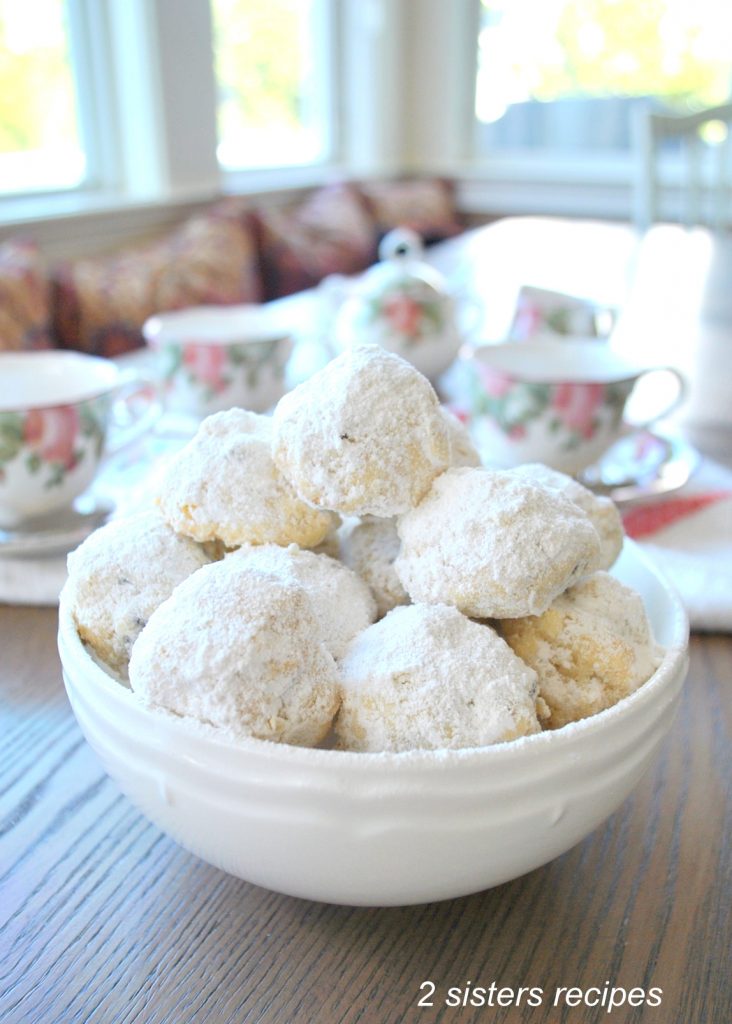 A white bowl filled with powdered covered ball-shaped cookies.