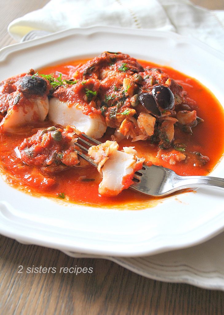 A forkful of cod smothered in tomato sauce on a white plate. by 2sistersrecipes.com