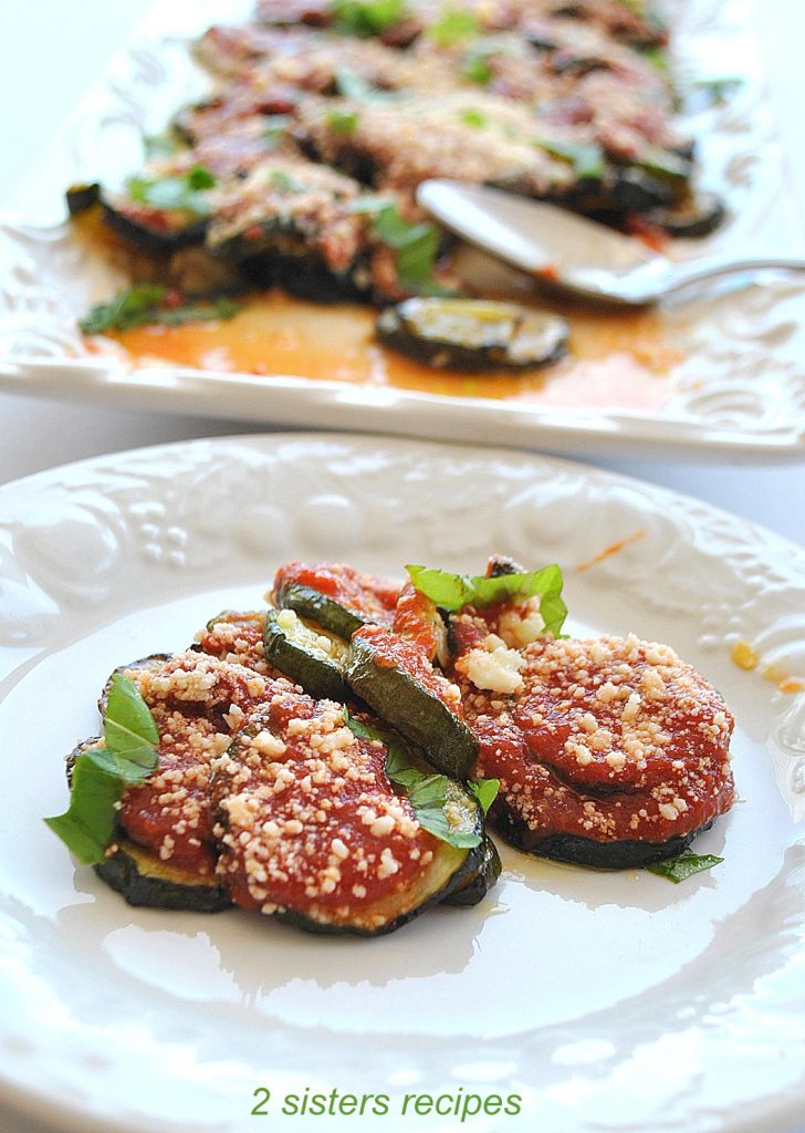 A white plate with a serving of roasted zucchini parmesan. 