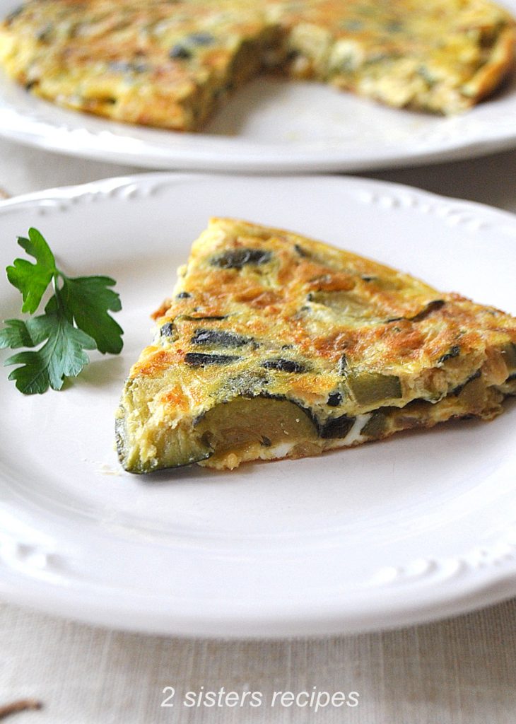 A slice of zucchini omelet served on a white plate.