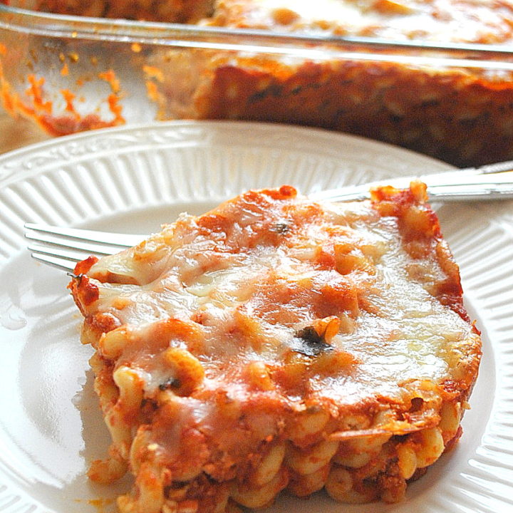 A serving of baked spaghetti on a white dinner plate.
