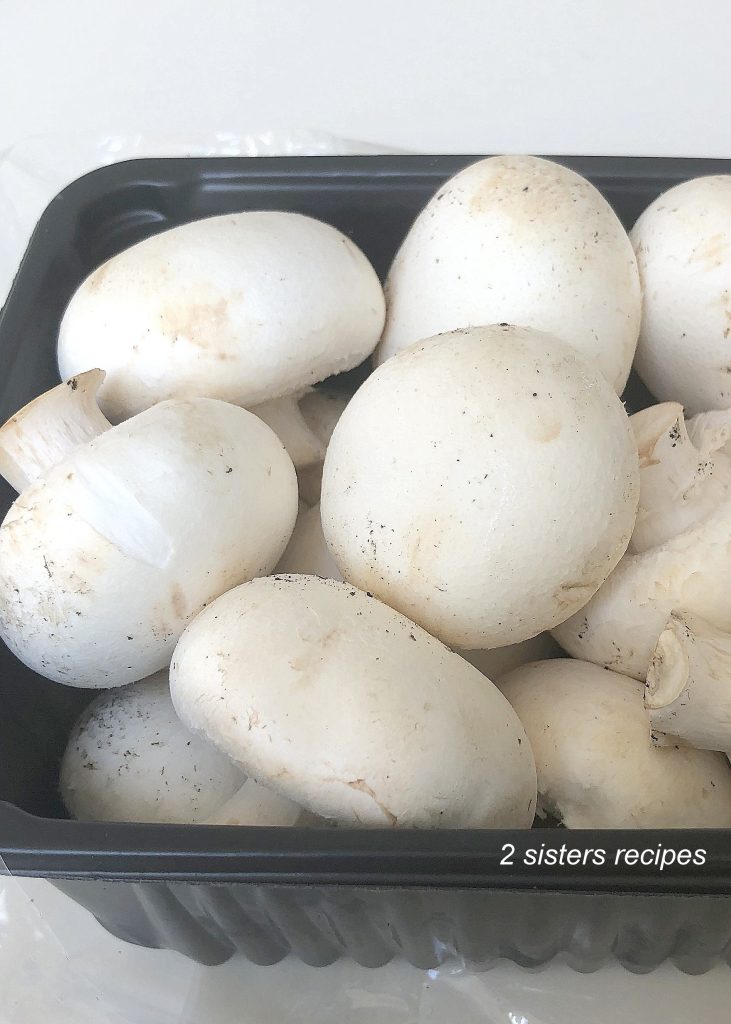 A basket of white mushrooms uncooked. by 2sistersrecipes.com 