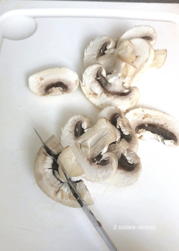 Mushrooms sliced on a white board. by 2sistersrecipes.com 