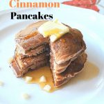 A white plate with a pile of apple cinnamon pancakes with butter and maple syrup on top.