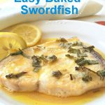 A baked swordfish served on a white plate with lemon sauce.