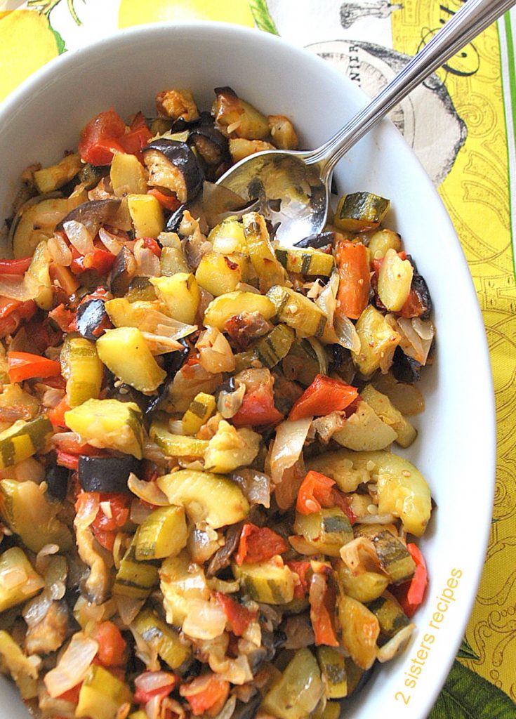 A white oval serving platter filled with mixed vegetables baked as ratatouille. 