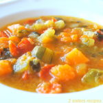 A white bowl filled with mixed veggies in a brothy soup.