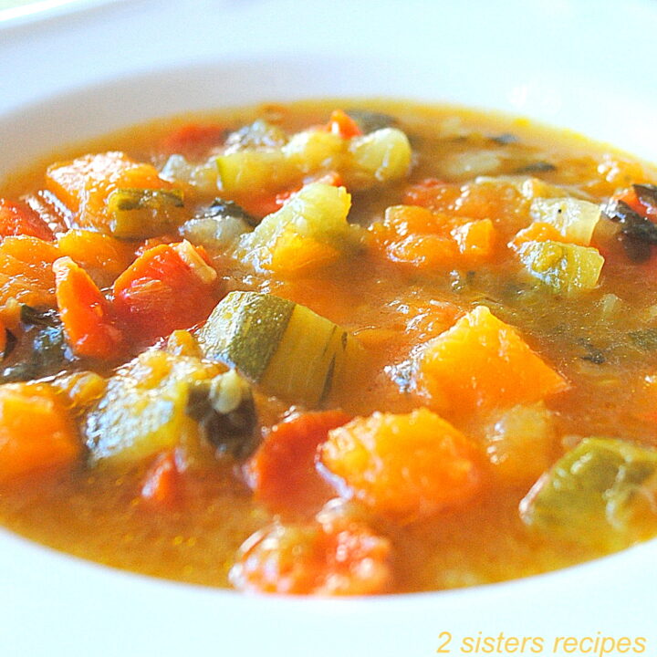 A white bowl filled with mixed veggies in a brothy soup.