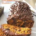A pumpkin bread covered with chocolate and chocolate chips sliced on a white platter.