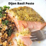 A serving of baked salmon with pesto sauce on top with a side of quinoa salad.