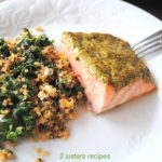 A serving on a white dinner plate with Baked Salmon and a quinoa salad on the side.