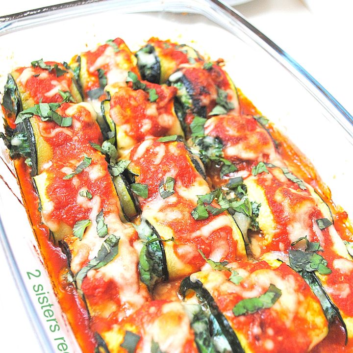 A glass casserole dish filled with Zucchini Rollatini with Spinach and Cheese, and topped with tomato sauce.