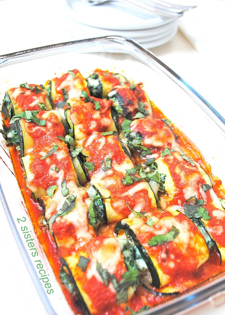 A glass casserole dish filled with Zucchini Rollatini with Spinach and Cheese, and topped with tomato sauce. 