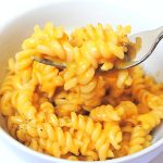 A white bowl and a forkful of butternut squash mac and cheese.