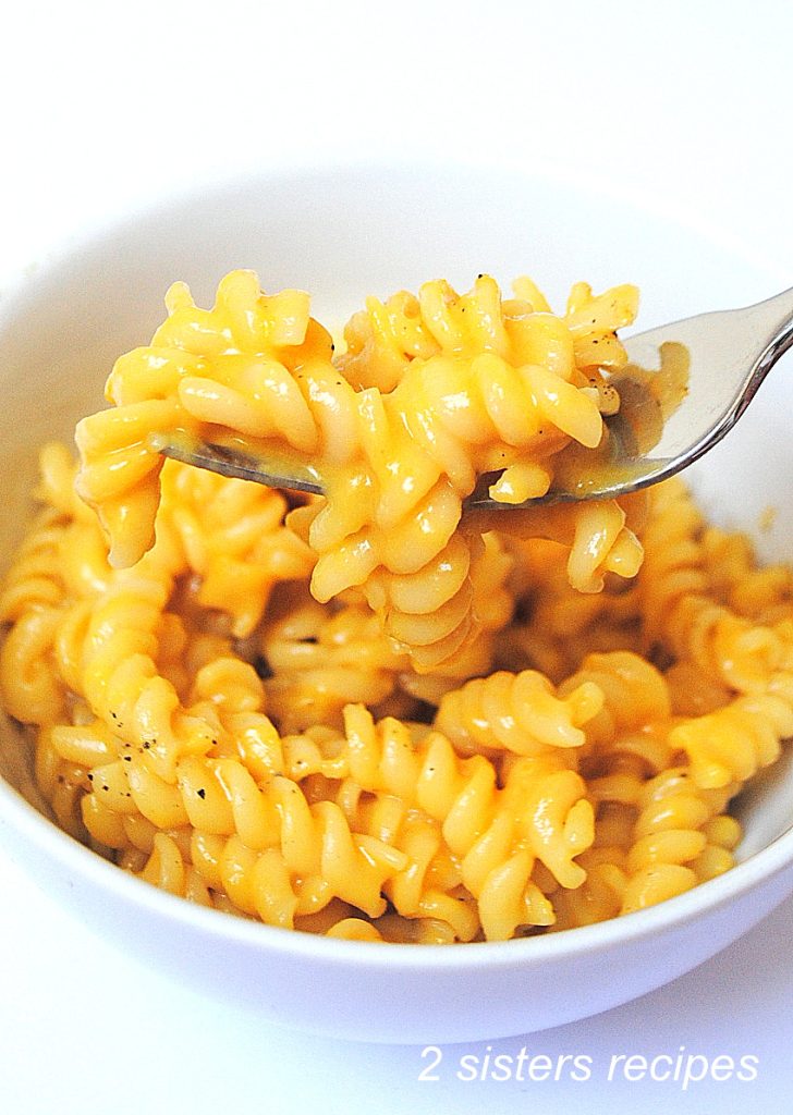 A white bowl and a forkful of butternut squash mac and cheese.