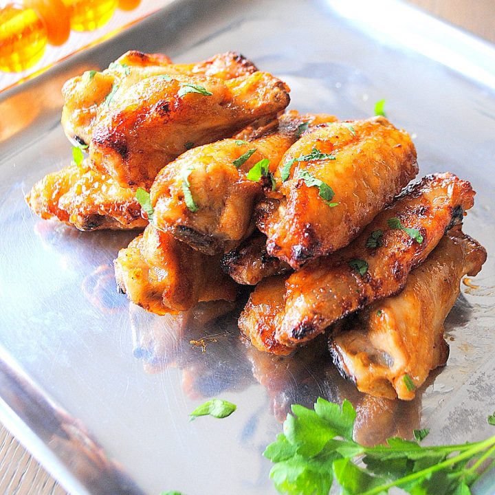 A silver platter with chicken wings piled on it.