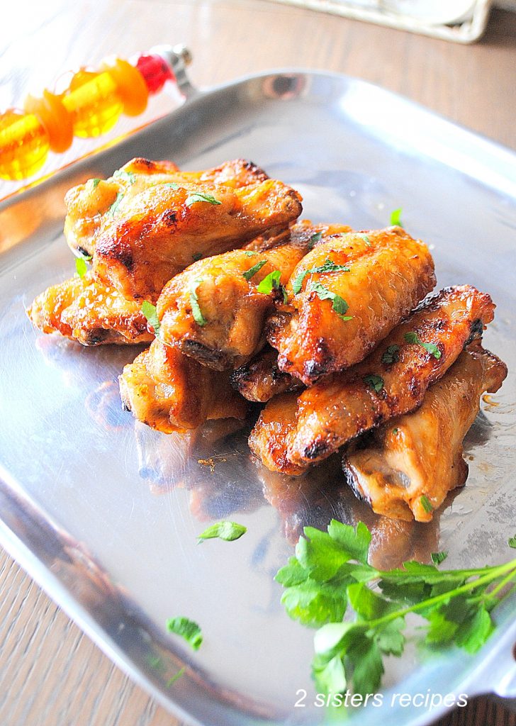 A silver platter with chicken wings piled on it. 