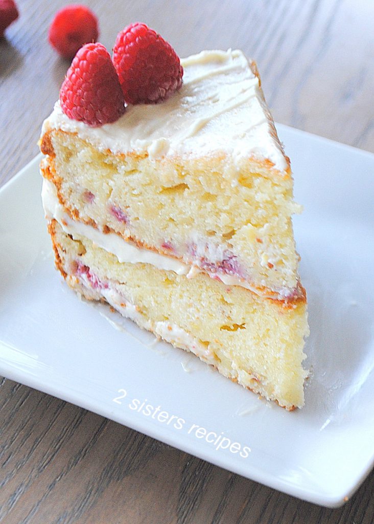 A slice of cake on a white square plate. by 2sistersrecipes.com