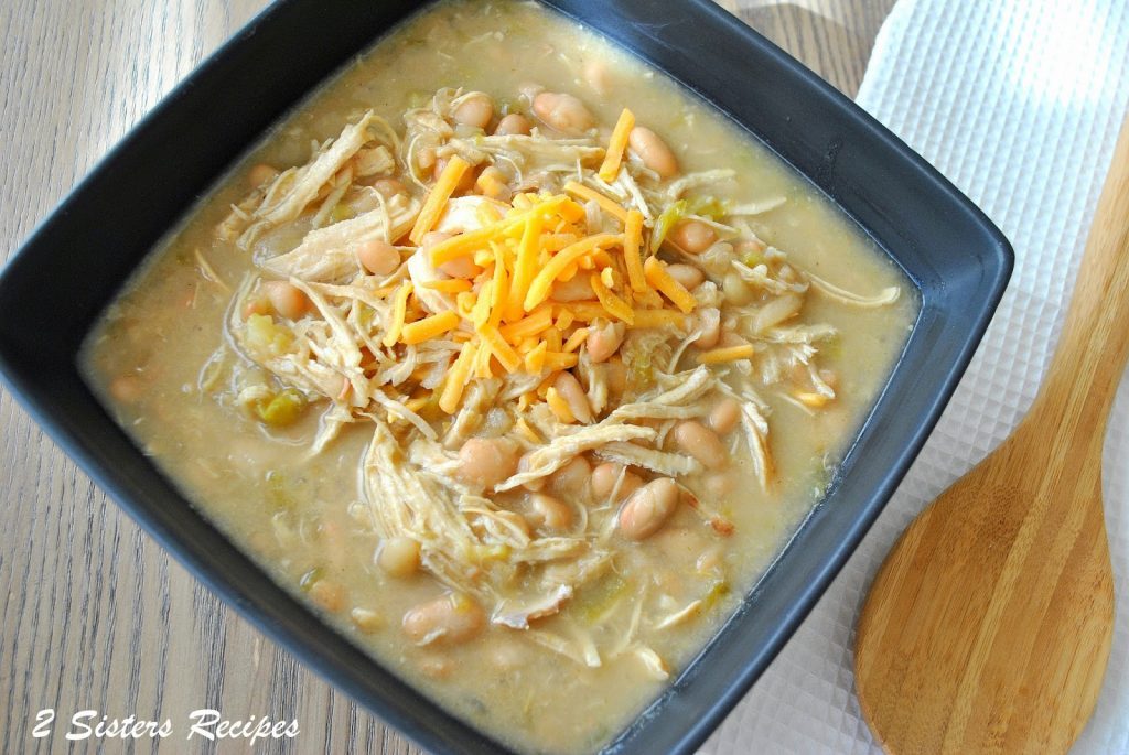 A close-up photo of chicken chili with shredded cheese on top.  by 2sistersrecipes.com 