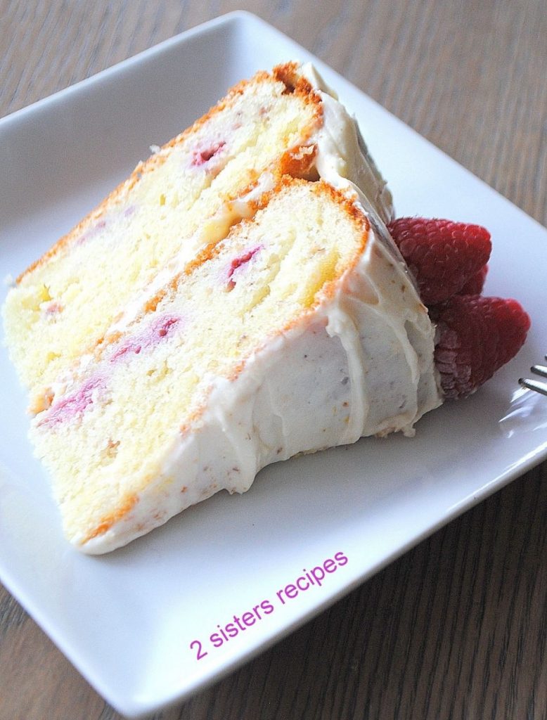 A slice of the Lemon Raspberry Cake on a white plate.  by 2sistersrecipes.com