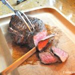 London Broil Steak is carved on a wooden carving board.