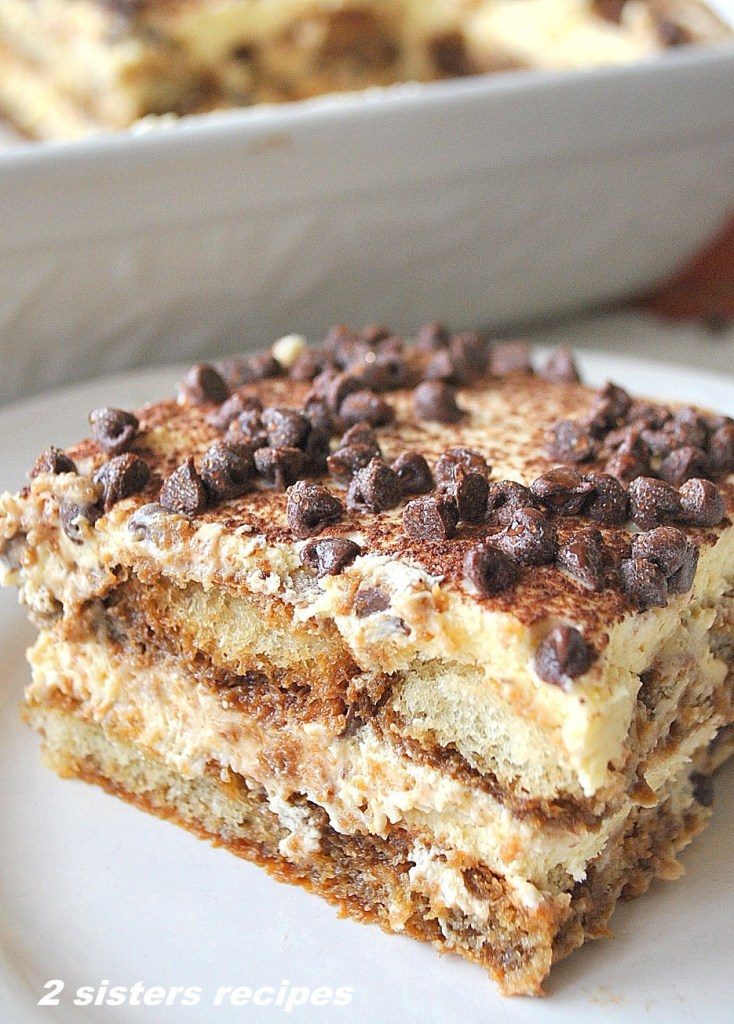 A square piece of Tiramisu cake on a white plate.