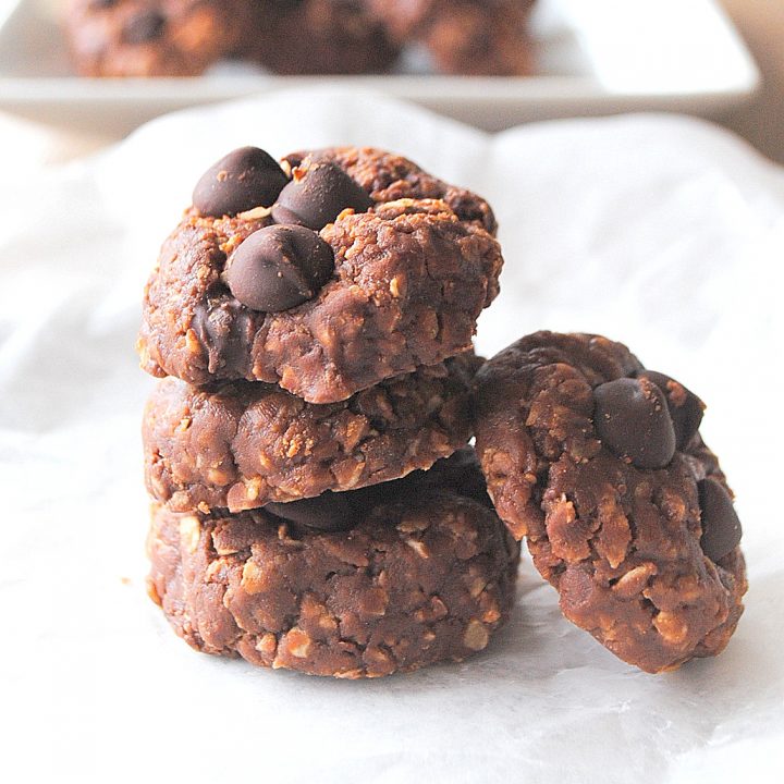 A pile of small chocolate chip cookies set on parchment paper,
