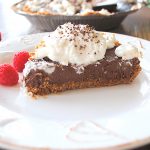 A slice of chocolate cream pie topped with whipped cream served on a white plate.